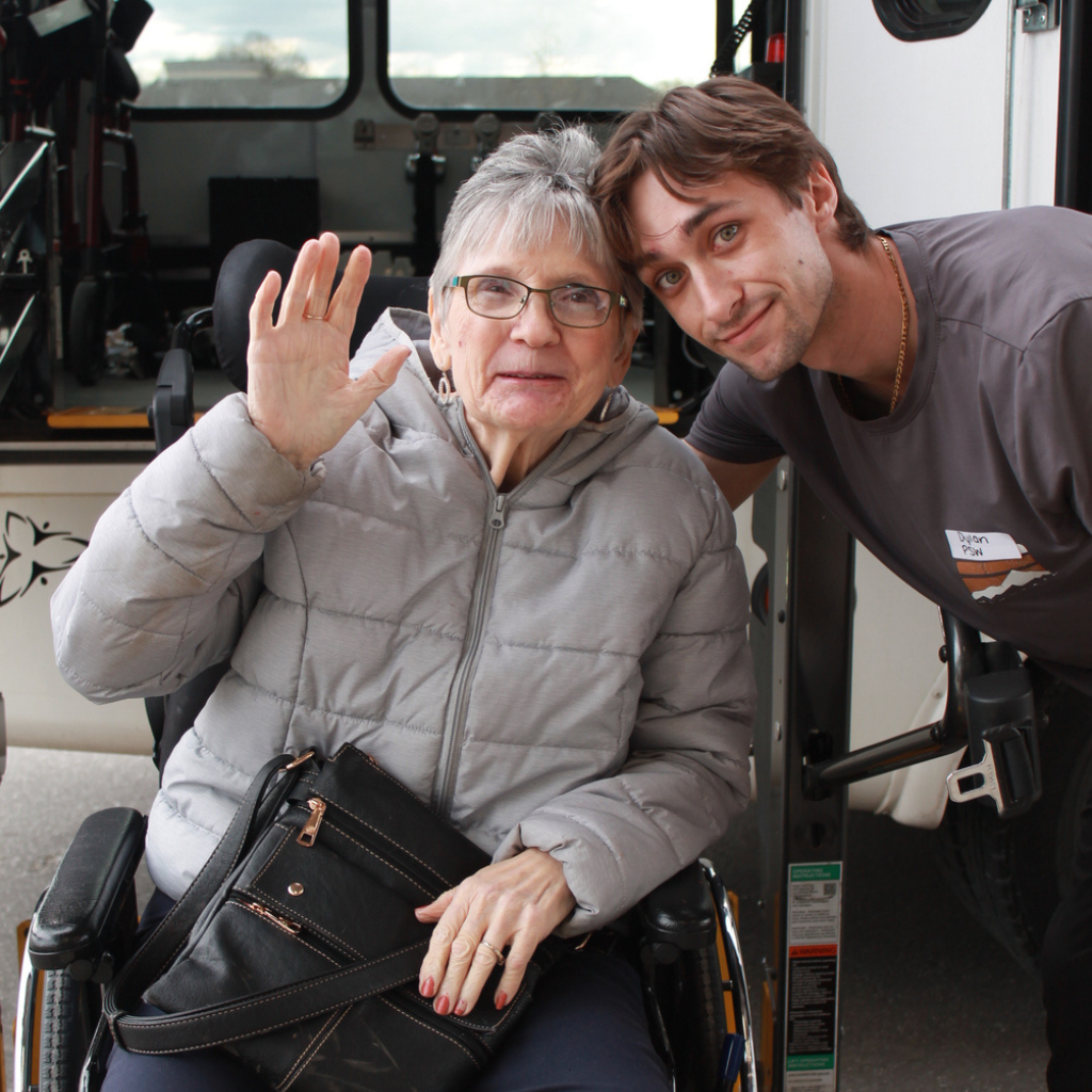 Resident waving with a team member, both smiling.